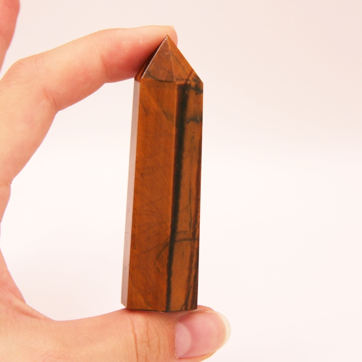 Naturalne tygrysie oko oszlifowane w formę obelisku - efekt chatoyancy.