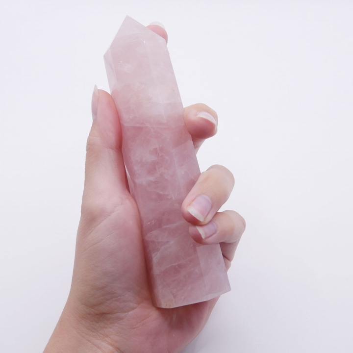 Smukła wieża z kwarcu różowego, symbol harmonii i spokoju, prezentowana na białym tle.