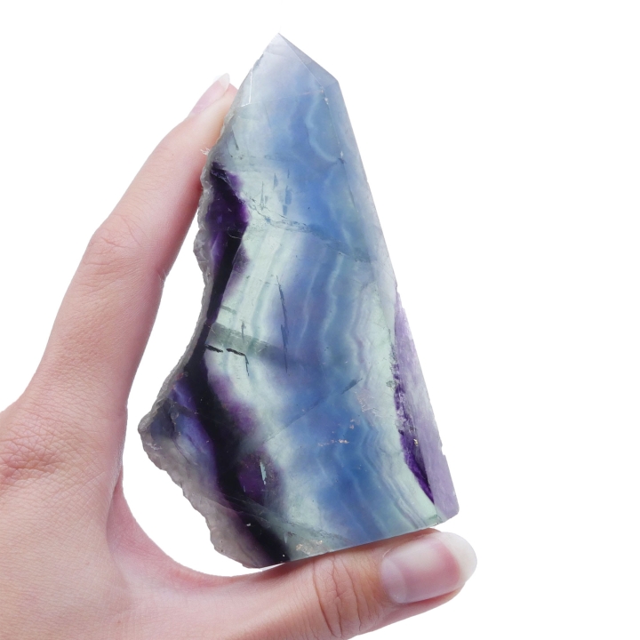 Stojąca forma z wielobarwnego fluorytu z polerowanymi ścianami i surową krawędzią na białym tle.