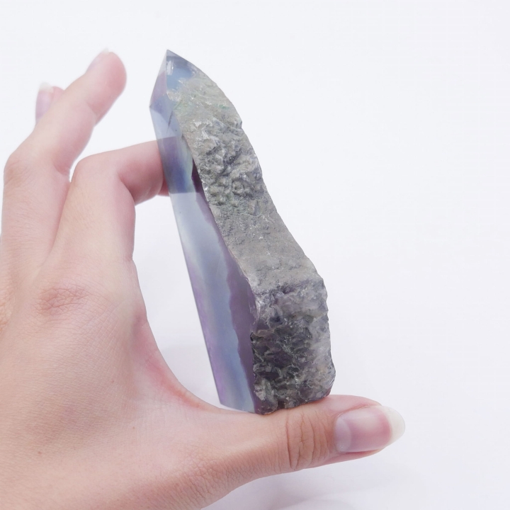 Zbliżenie na surową, nieobrobioną krawędź ozdobnej formy z fluorytu.