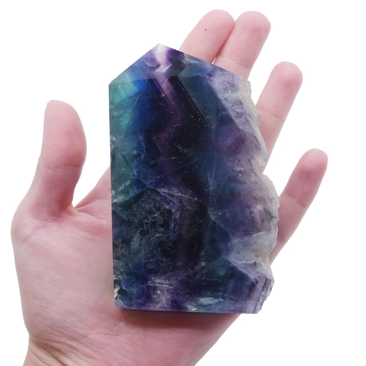 Prześwitujący plaster fluorytu na białym tle, ukazujący wewnętrzne pasma kolorów.