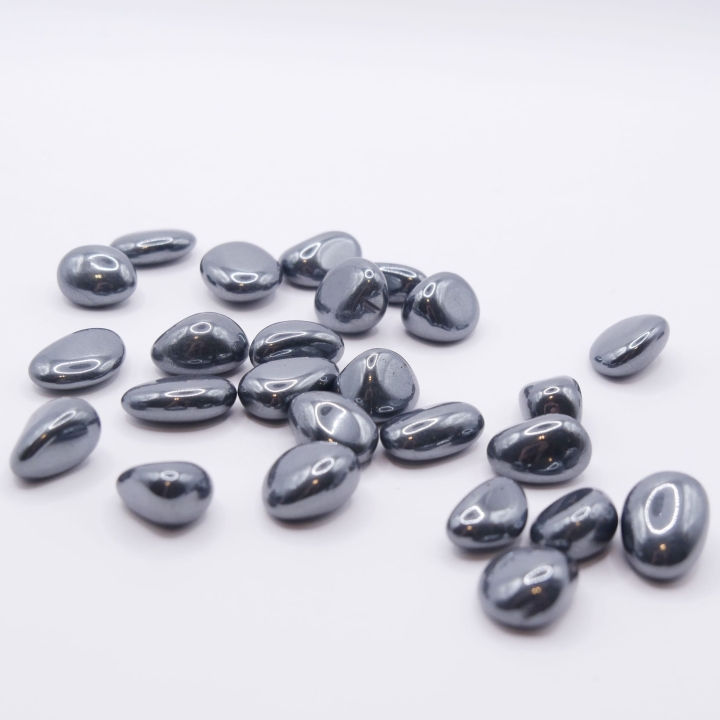 Grupa małych, polerowanych otoczaków hematytu, ukazująca ich nieregularne kształty i metaliczny blask.