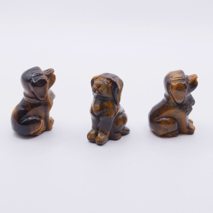 Ręcznie rzeźbiona figurka psa z naturalnego tygrysiego oka na białym tle.