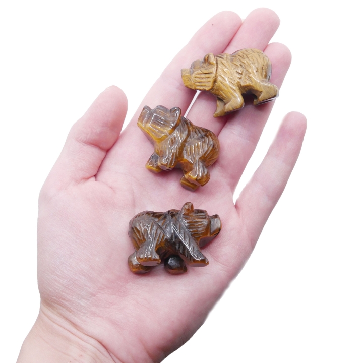 Figurka niedźwiedzia z tygrysiego oka trzymana w dłoni, aby pokazać jej rozmiar i detale.