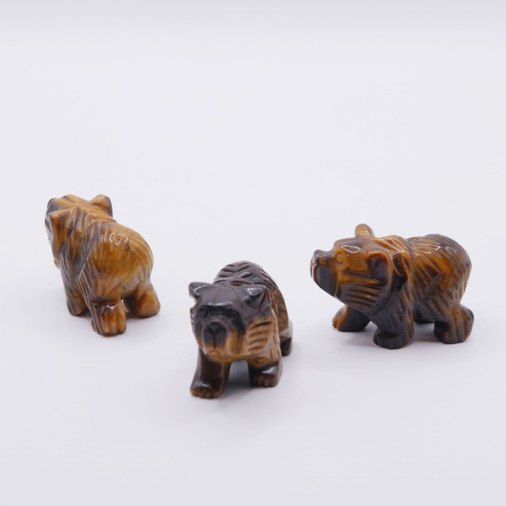 Ręcznie rzeźbiona figurka niedźwiedzia z naturalnego tygrysiego oka na białym tle.