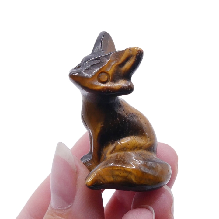 Zbliżenie na polerowaną powierzchnię figurki lisa, widoczny efekt kociego oka tygrysiego oka.