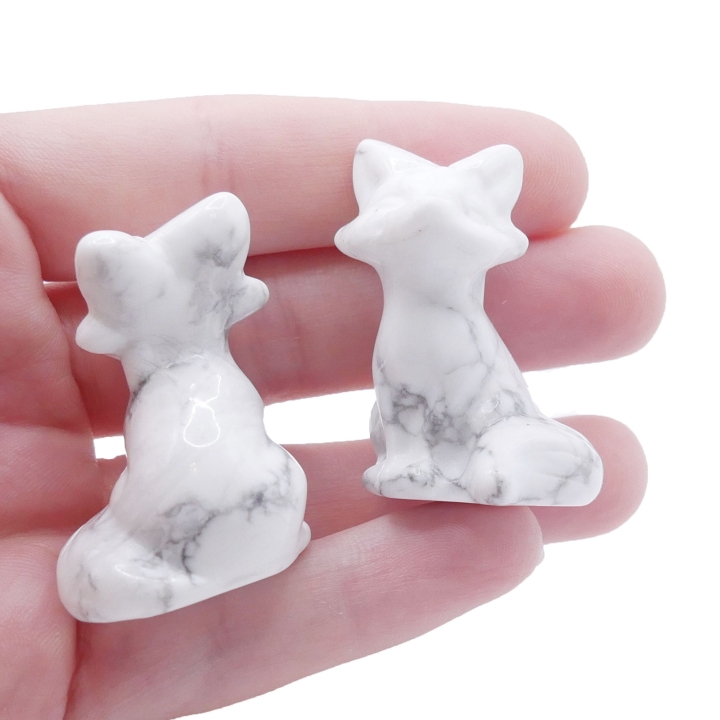 Ręcznie rzeźbiona figurka lisa z białego howlitu z szarymi żyłkami na białym tle.
