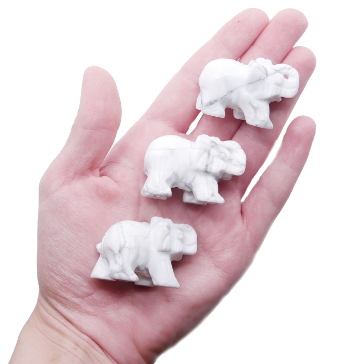 Ręcznie rzeźbiona figurka słonia z białego howlitu z szarymi żyłkami na białym tle.