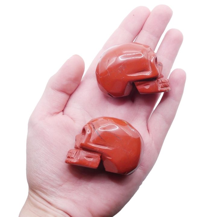 Zbliżenie na polerowaną powierzchnię czaszki z czerwonego jaspisu, widoczne detale rzeźbienia.