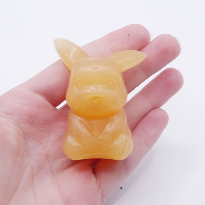 Polerowana figurka Pikachu z pomarańczowego kamienia, widok z przodu.