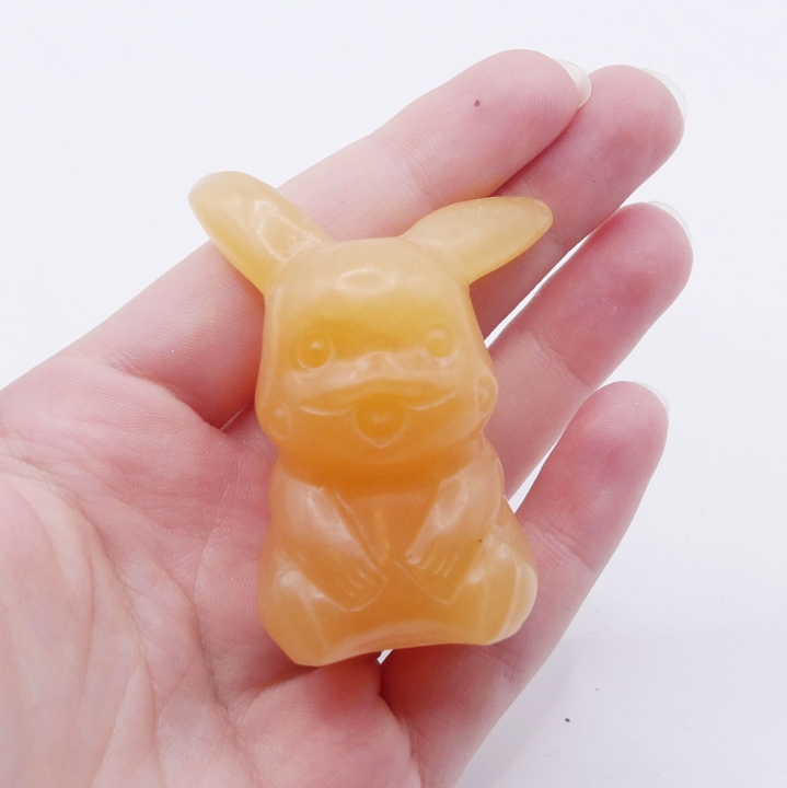 Zbliżenie na figurkę z kalcytu pomarańczowego, ukazujące jej gładką powierzchnię i połysk.