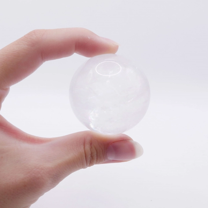 Zbliżenie na unikalne, wewnętrzne inkluzje i struktury w kuli z kryształu górskiego.