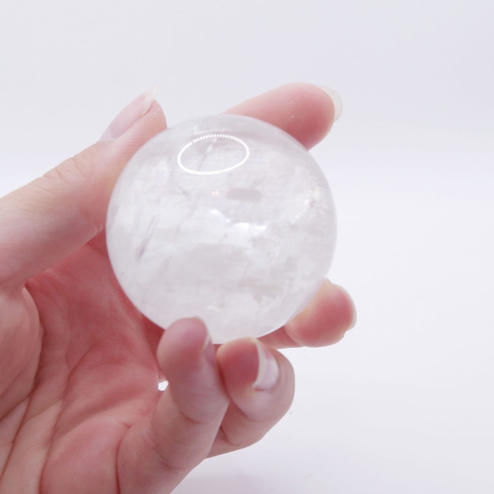 Gładka kula z przezroczystego kwarcu górskiego, odbijająca światło.