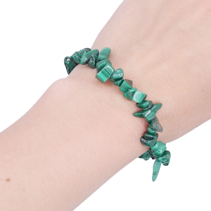 Elastyczna bransoletka z nieregularnych kawałków (sieczki) zielonego malachitu na białym tle.