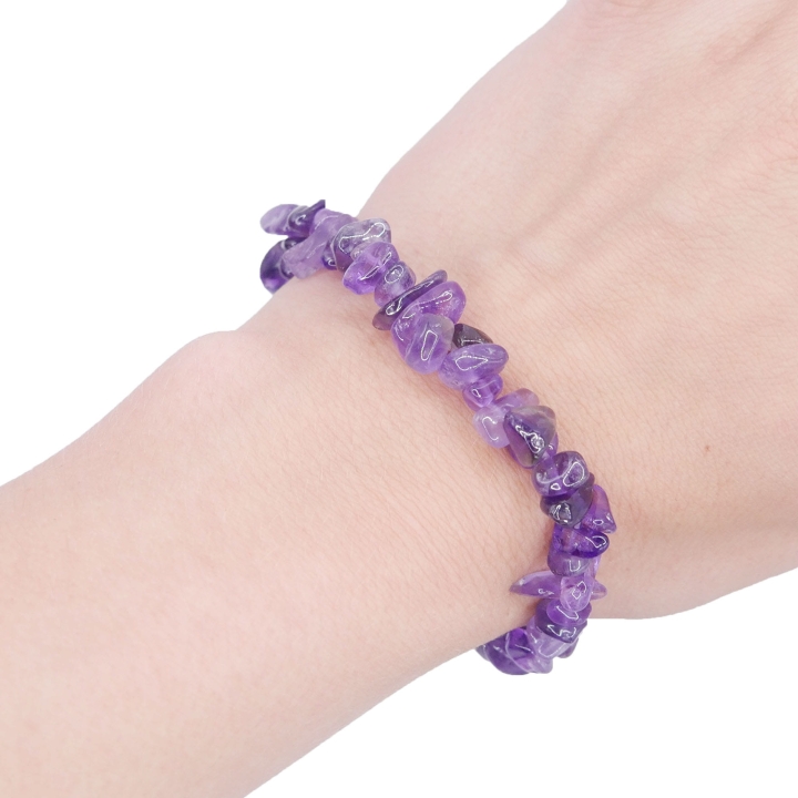 Elastyczna bransoletka z nieregularnych kawałków (sieczki) fioletowego ametystu na białym tle.