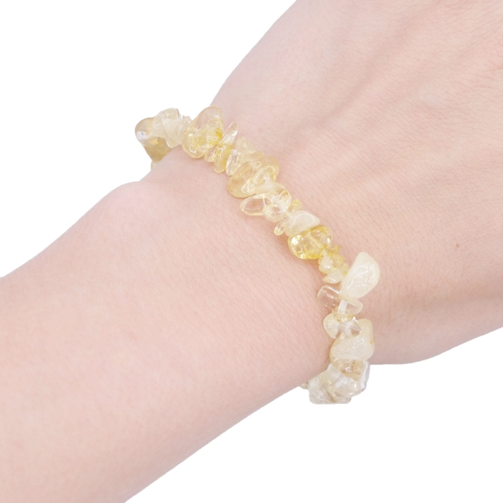 Elastyczna bransoletka z nieregularnych kawałków (sieczki) jasnożółtego cytrynu na białym tle.