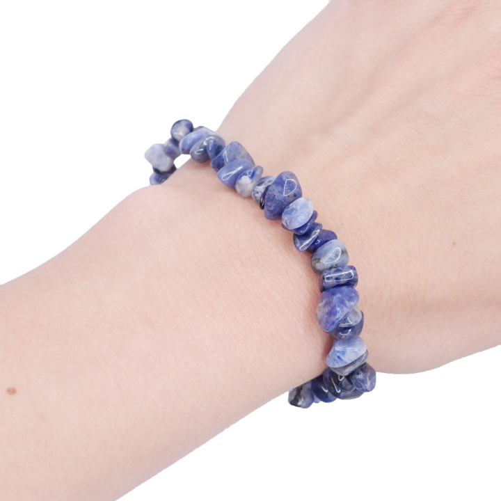 Elastyczna bransoletka z nieregularnych kawałków (sieczki) niebieskiego sodalitu na białym tle.