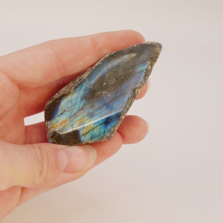 Kontrast między surową, naturalną fakturą a gładką, polerowaną powierzchnią bryłki labradorytu.