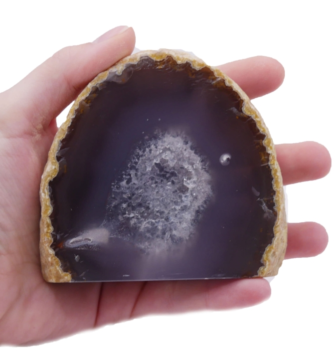 Surowa bryłka szarego agatu z jedną polerowaną ścianą i płaską podstawą na białym tle.