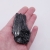 Fragment czarnego minerału o głębokiej czerni i naturalnej, chropowatej fakturze.