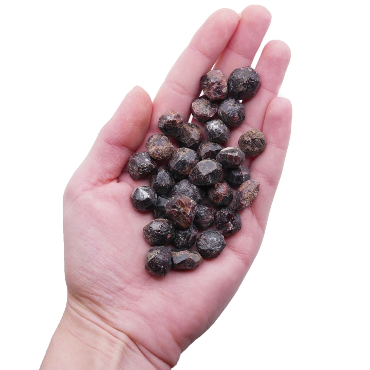 Mała, surowa bryłka granatu o głębokim, bordowym kolorze na białym tle.