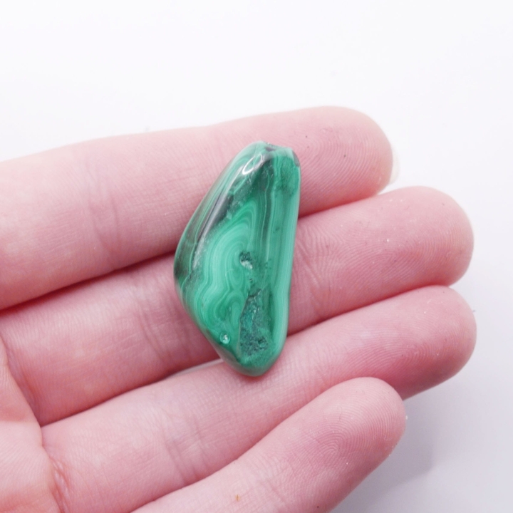 Zbliżenie na koncentryczne kręgi i pasma widoczne na polerowanej powierzchni malachitu.