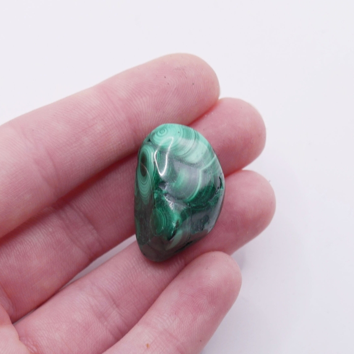 Unikatowy okaz bębnowanego malachitu, prezentujący różnorodność odcieni zieleni.