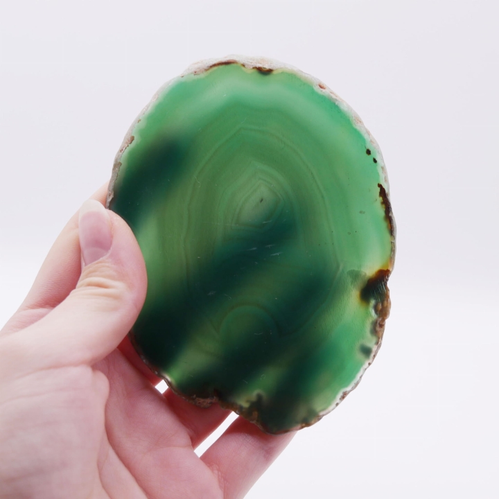 Surowa, naturalna krawędź stanowiąca ramę dla gładkiej tafli zielonego kamienia.