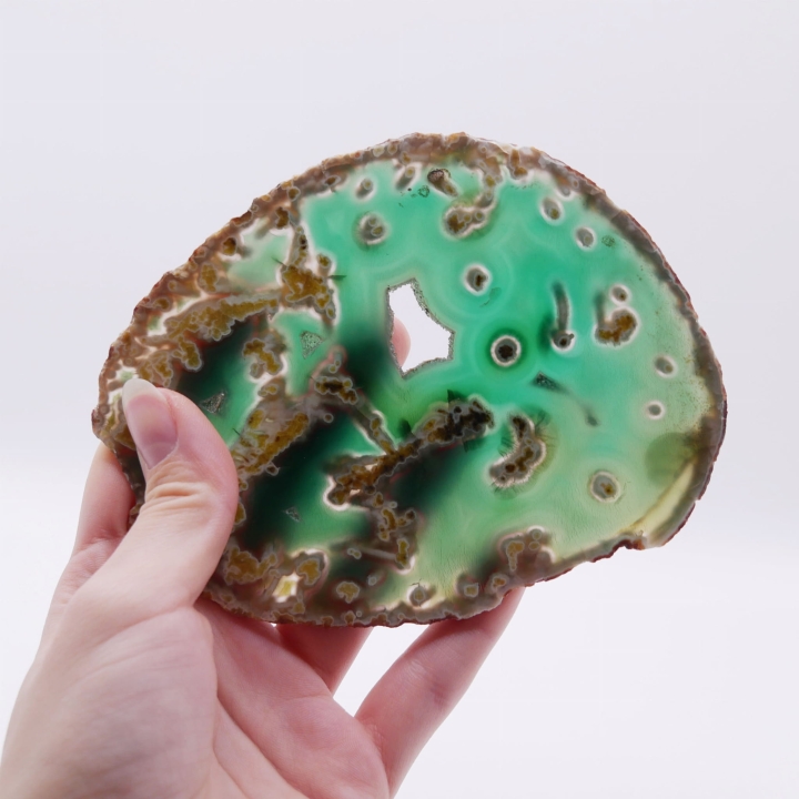 Surowa krawędź kontrastująca z gładką, lśniącą powierzchnią zielonego kamienia.