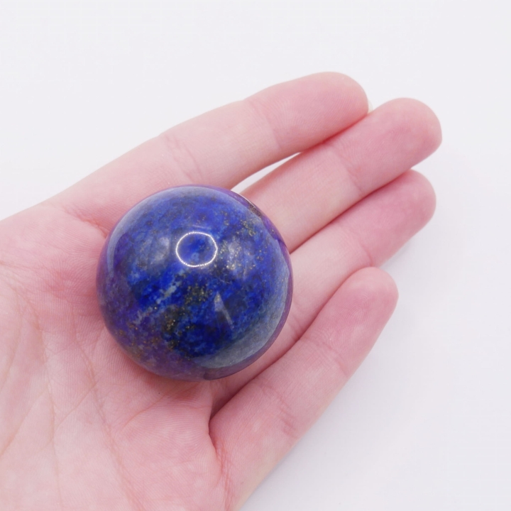 Zbliżenie na złote drobiny pirytu na powierzchni kuli z lapisu lazuli.