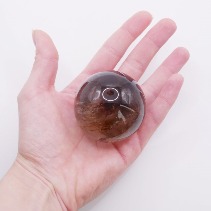 Zbliżenie na naturalne mgiełki i inkluzje wewnątrz sfery z kwarcu dymnego.