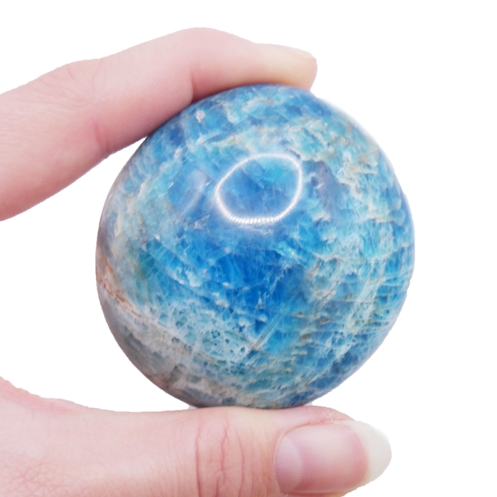 Polerowany otoczak apatytu o intensywnym, morskim odcieniu na białym tle.