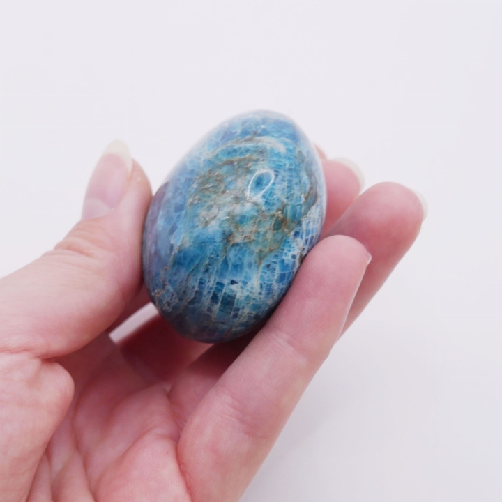 Gładki, morski minerał o zaokrąglonym kształcie, trzymany w dłoni.