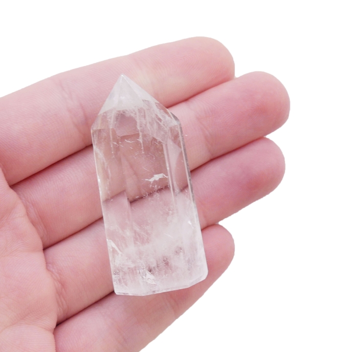 Smukły obelisk z kryształu górskiego o przejrzystej strukturze na białym tle.