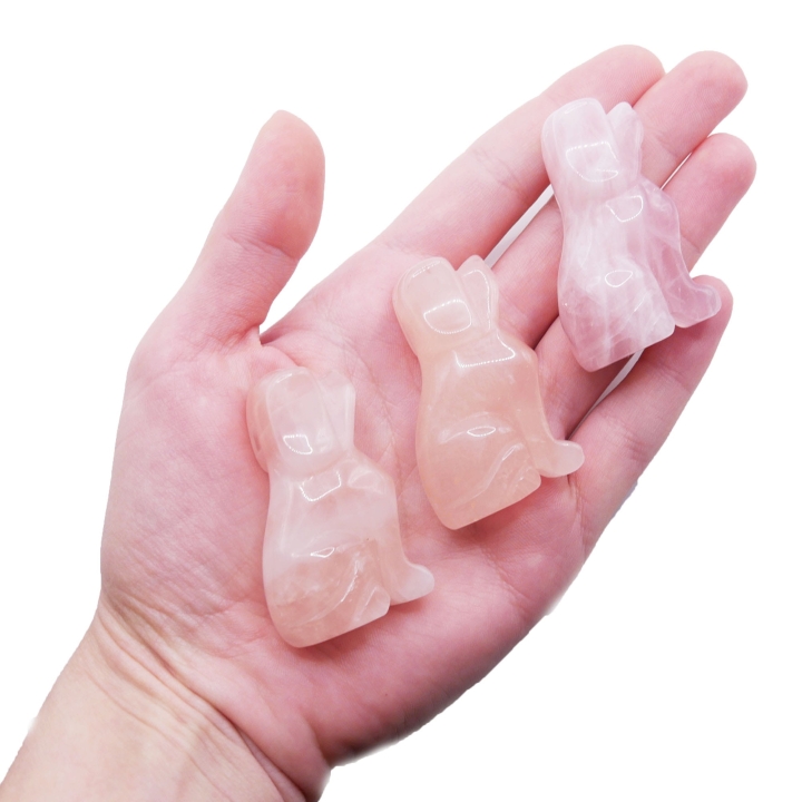 Ręcznie rzeźbiona figurka psa z naturalnego kwarcu różowego na białym tle.