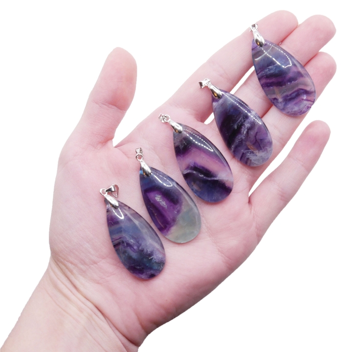 Półprzezroczysta zawieszka z fluorytu w kształcie kropli na białym tle.