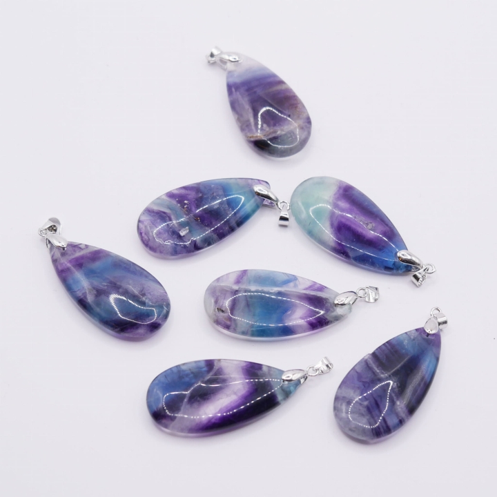 Zbliżenie na pasma fioletu i zieleni wewnątrz polerowanej łezki fluorytu.