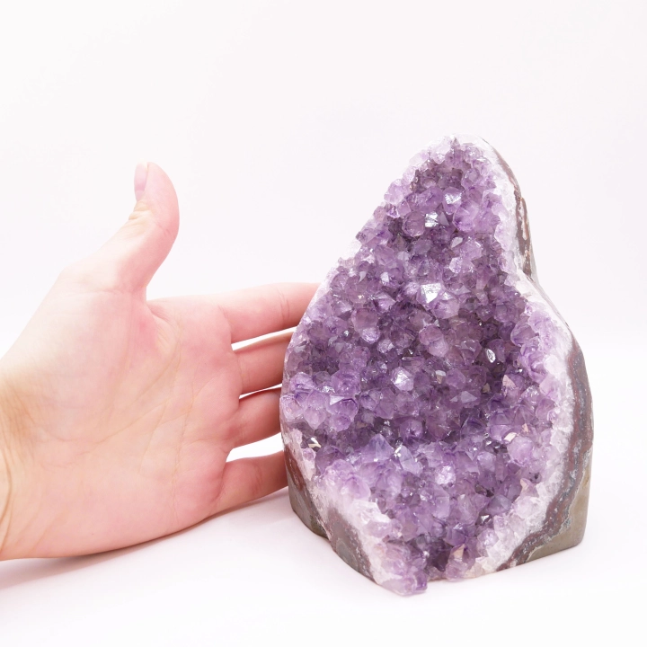 Zbliżenie na krystaliczny front ametystu kontrastujący z surową skałą z tyłu.