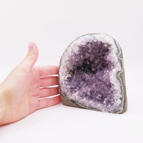 Zbliżenie na lśniące wnętrze ametystu kontrastujące z surową skałą na zewnątrz.