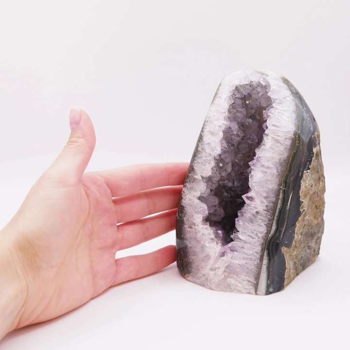 Zbliżenie na krystaliczny front ametystu kontrastujący z surową skałą z tyłu.