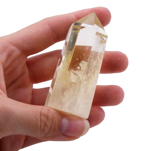 Smukły obelisk z naturalnego cytrynu o jasnej, żółtej barwie na białym tle.