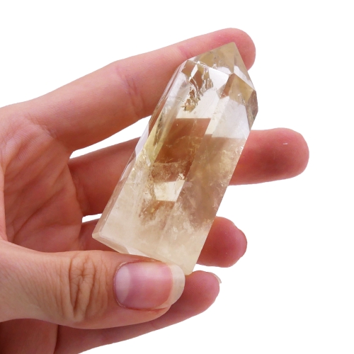 Polerowany obelisk z jasnego cytrynu o smukłej formie na białym tle.