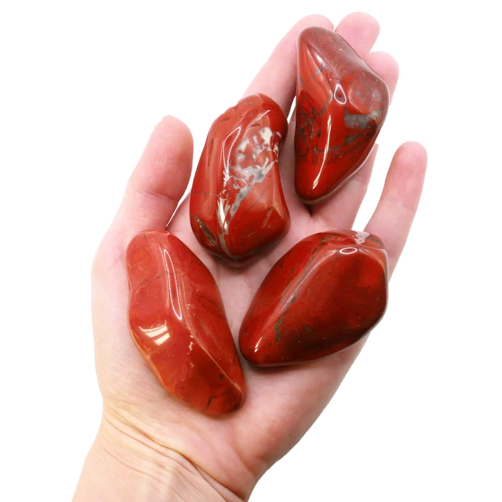 Duży, polerowany otoczak z czerwonego jaspisu o intensywnej, ceglastej barwie na białym tle.