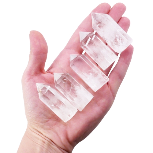 Polerowane obeliski z kryształu górskiego o smukłej, geometrycznej formie na białym tle.