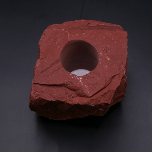 Świecznik z surowego jaspisu czerwonego – masywna bryła o intensywnej, ceglastej barwie.