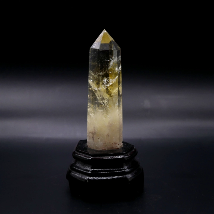 Obelisk z cytrynu na ciemnej drewnianej podstawce – elegancka dekoracja z naturalnego minerału.
