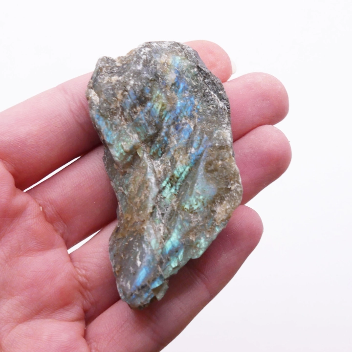 Kontrast między surową fakturą a polerowaną powierzchnią labradorytu na białym tle.