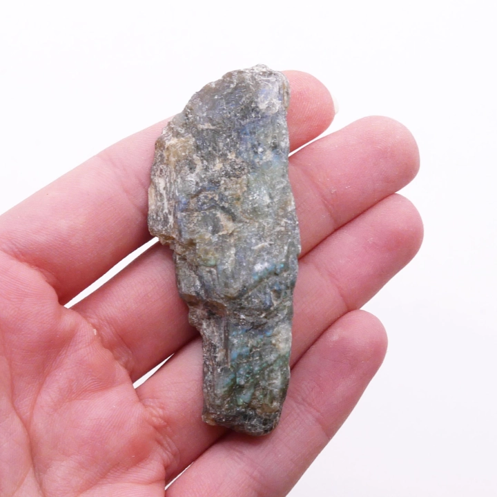 Kontrast surowej i polerowanej strony labradorytu – naturalna bryła ukazująca pierwotną strukturę skalną.