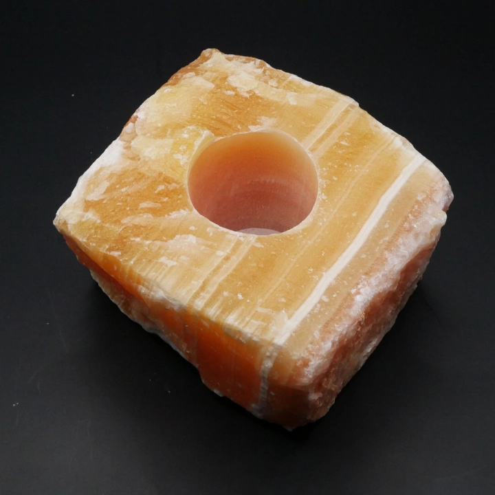 Świecznik z surowego kalcytu pomarańczowego nr 014 – masywna, kwadratowa bryła z miejscem na tealight.